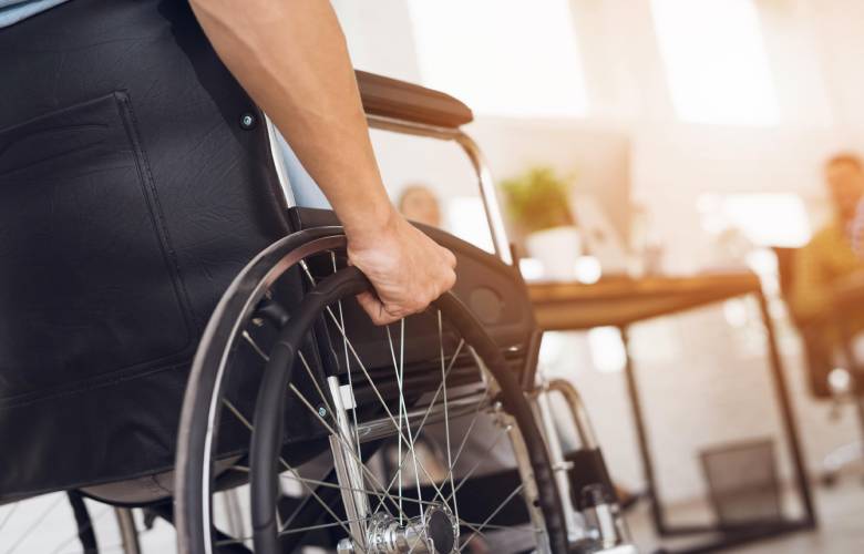 Detail van een rolstoel waar een man inzit. Hij krijgt hier een terugbetaling voor omdat hij in aanmerking komt door zijn ziekte.