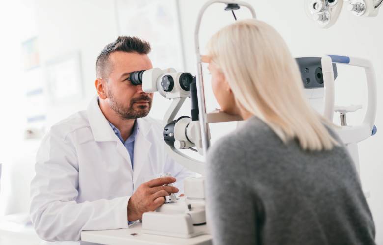 Opticien controleert de sterkte van de ogen van een vrouw zodat ze een terugbetaling krijgt van haar bril.