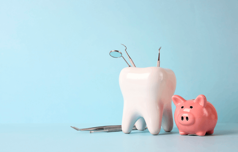 Een klein spaarvarken staat naast een grote porseleinen tand met tandartsgereedschap.