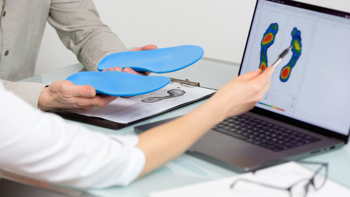 Orthopedist toont steunzolen naast een digitale voetanalyse.