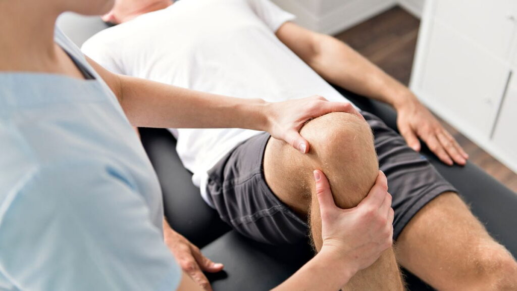 Kinesist behandelt de knie van een patiënt tijdens een sessie.